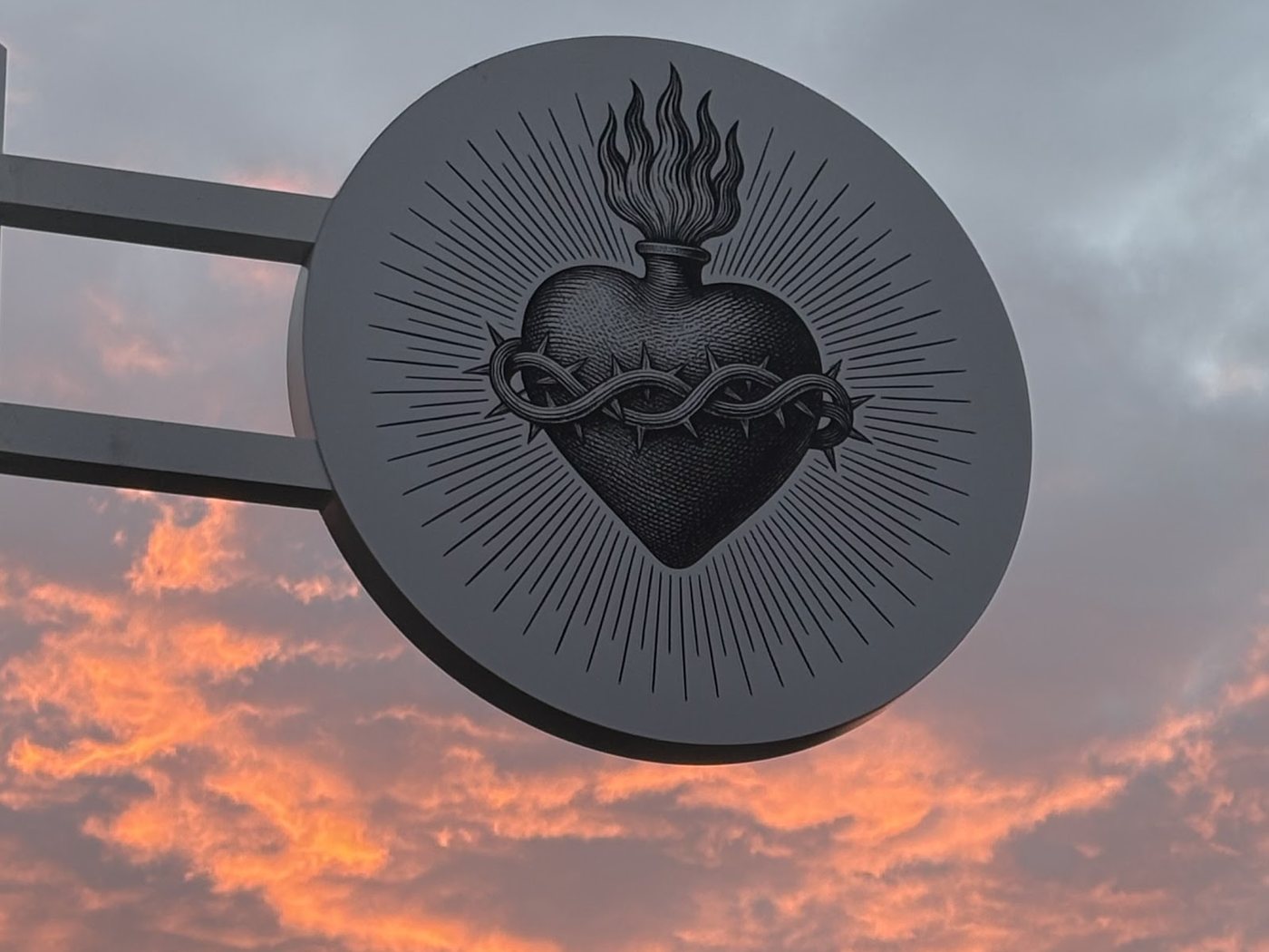 L'enseigne cœur sacré du café, illuminée contre un ciel de coucher de soleil