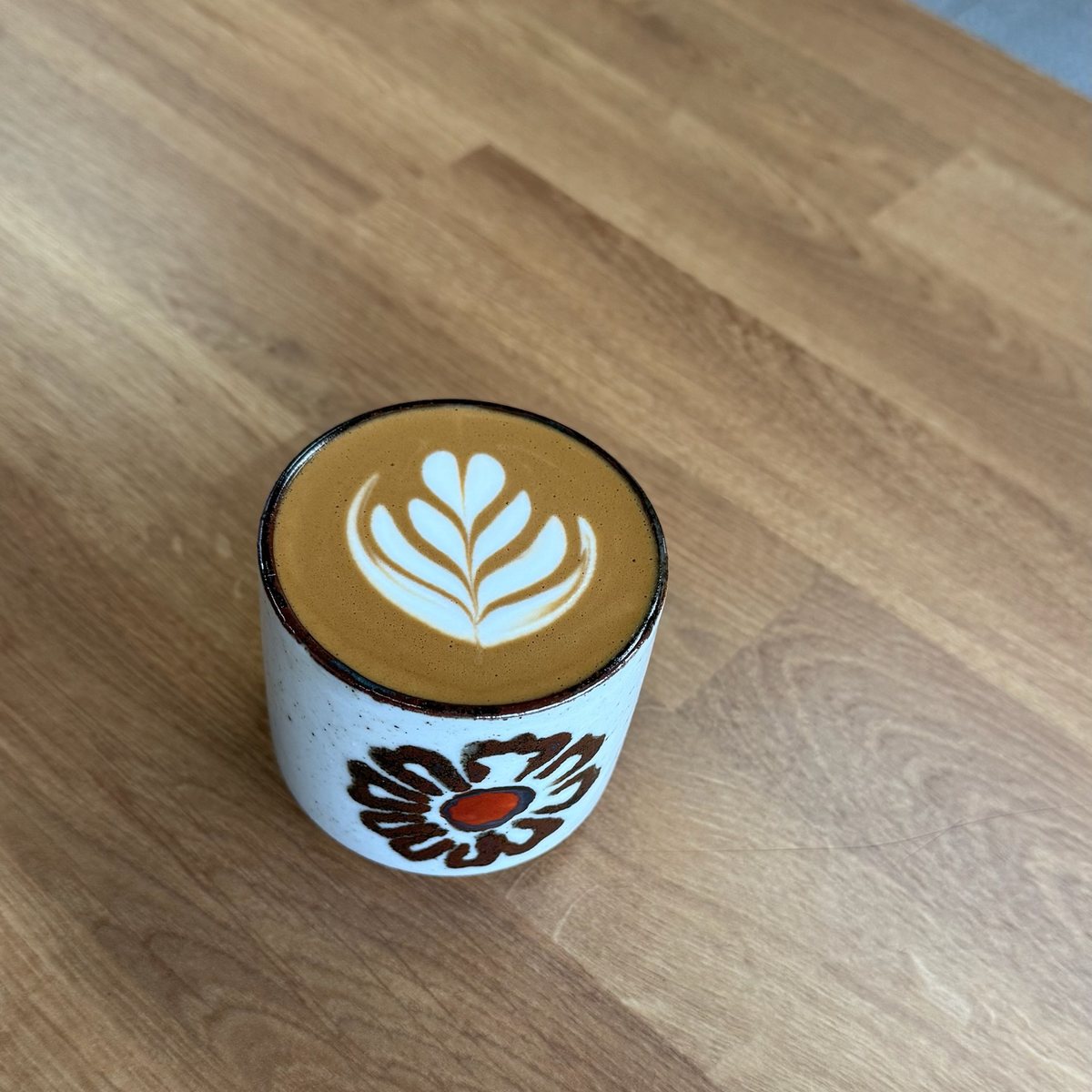 Matcha latte avec art en feuille, servi sur une table en bois