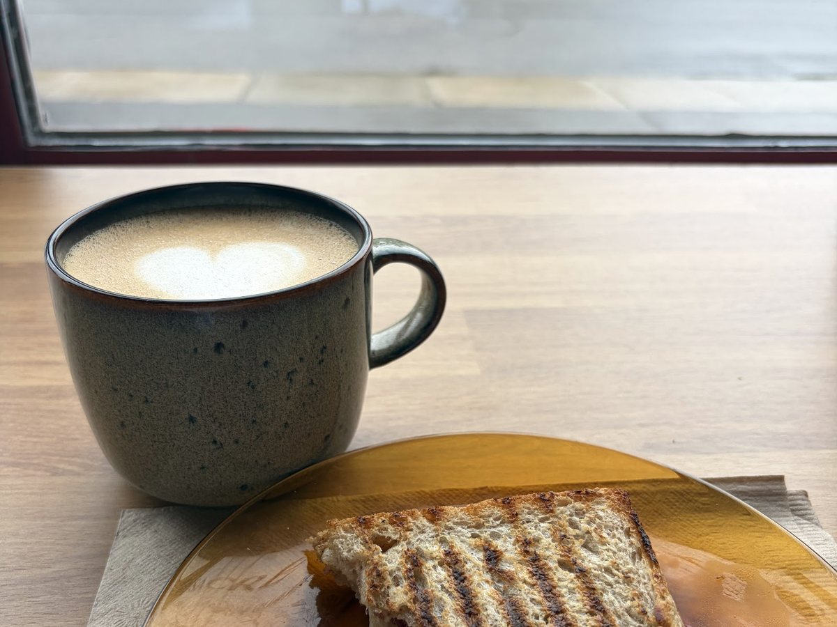 Sandwich grillé et café servis près d'une fenêtre